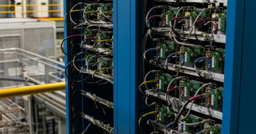 Rows of server racks and cables inside a data center, representing the physical infrastructure behind cloud AI services.